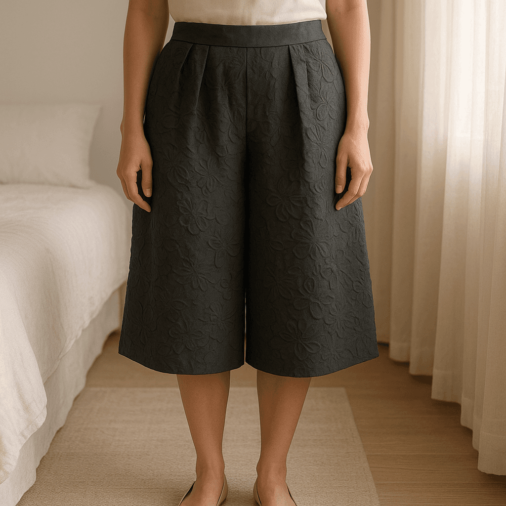 Gonna Stefanel nera lavorazione damascata tg.46 in piedi, rivolto verso la fotocamera, in una camera da letto con luce soffusa e luce naturale che filtra dalla finestra.