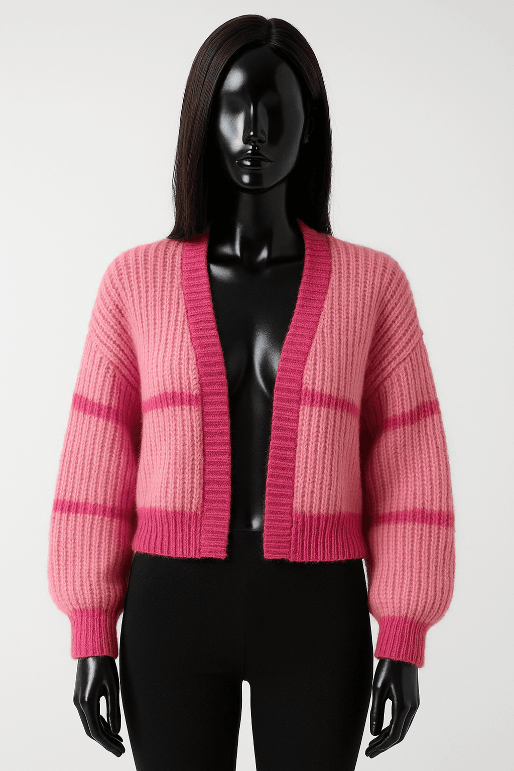 eine glänzende schwarze Kunststoffpuppe ohne Gesichtszüge in Boleros Rosa/Pink aufrecht stehend, der Kamera zugewandt, mit schlanker Figur, in einem sauberen Fotostudio mit nahtlosem weißen Hintergrund und Softbox-Beleuchtung.