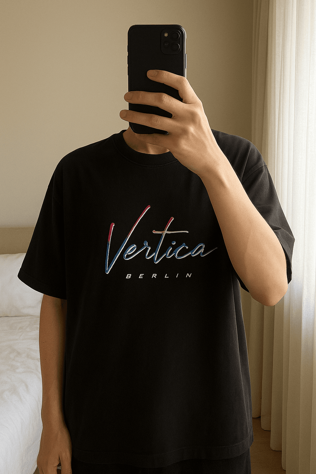Vertere Berlin T-Shirt aufrecht stehend, der Kamera zugewandt, in einem sanft beleuchteten Schlafzimmer, mit natürlichem Licht, das durch ein Fenster fällt.