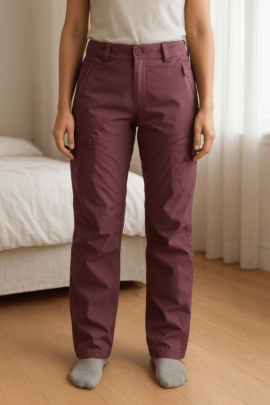 Pantaloni snowboard in piedi, rivolto verso la fotocamera, in una camera da letto con luce soffusa e luce naturale che filtra dalla finestra.