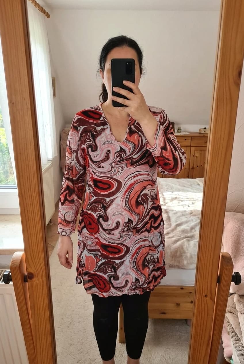 Jolie tunique robe légère taille 44 debout, face à la caméra, dans une chambre à la lumière douce, avec une lumière naturelle filtrant par la fenêtre.