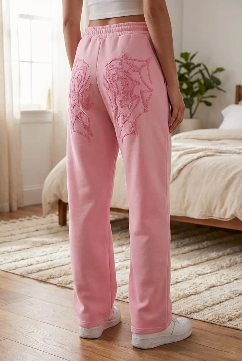 Jogging rose debout, face à la caméra, dans une chambre à la lumière douce, avec une lumière naturelle filtrant par la fenêtre.