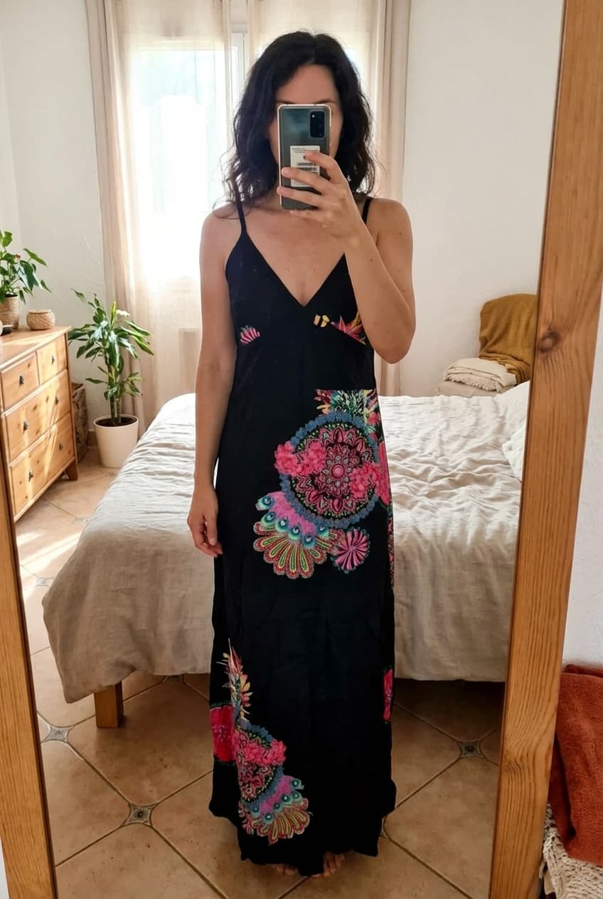 Sublime robe longue légère noire taille 38 debout, face à la caméra, dans une chambre à la lumière douce, avec une lumière naturelle filtrant par la fenêtre.