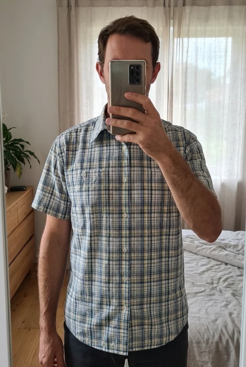 Chemise manche courte, Wrangler, taille Xl debout, face à la caméra, dans une chambre à la lumière douce, avec une lumière naturelle filtrant par la fenêtre.