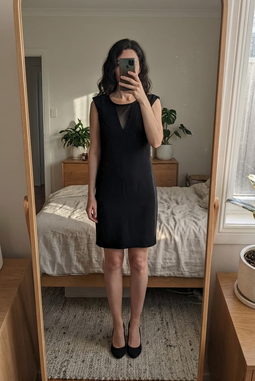 Robe Zara debout, face à la caméra, dans une chambre à la lumière douce, avec une lumière naturelle filtrant par la fenêtre.