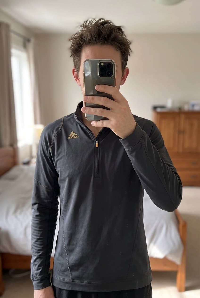 Haut Adidas noir Supernova mixte debout, face à la caméra, dans une chambre à la lumière douce, avec une lumière naturelle filtrant par la fenêtre.