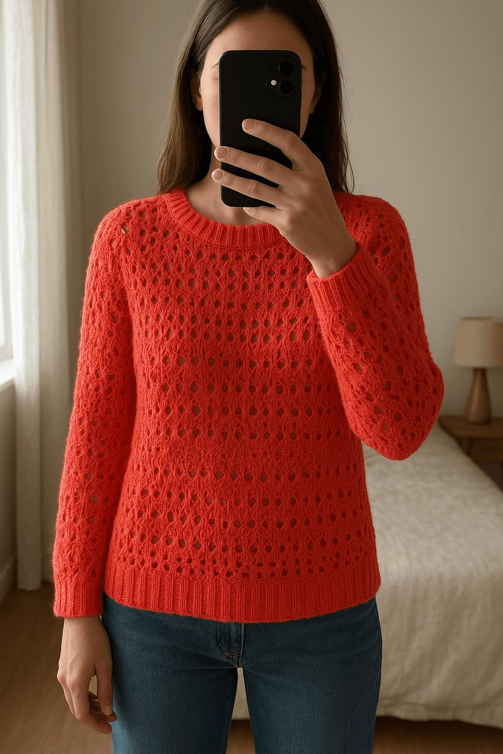 Maglione traforato Hollister – colore corallo in piedi, rivolto verso la fotocamera, in una camera da letto con luce soffusa e luce naturale che filtra dalla finestra.