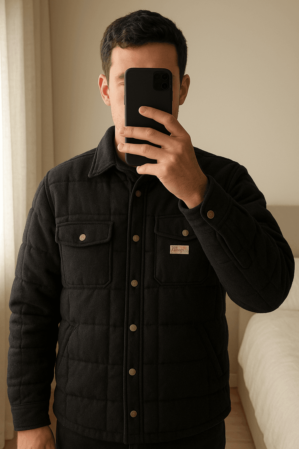 Piumino Fay Archives in piedi, rivolto verso la fotocamera, in una camera da letto con luce soffusa e luce naturale che filtra dalla finestra.