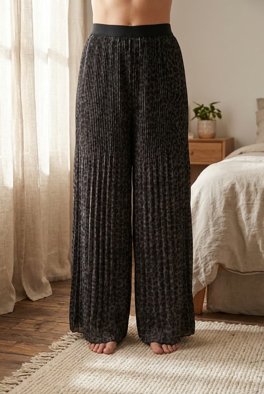 Jupe longue plissée debout, face à la caméra, dans une chambre à la lumière douce, avec une lumière naturelle filtrant par la fenêtre.