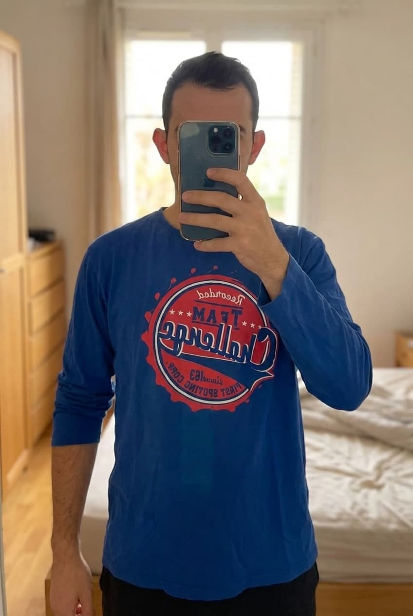 Pull homme alban briwn XL debout, face à la caméra, dans une chambre à la lumière douce, avec une lumière naturelle filtrant par la fenêtre.